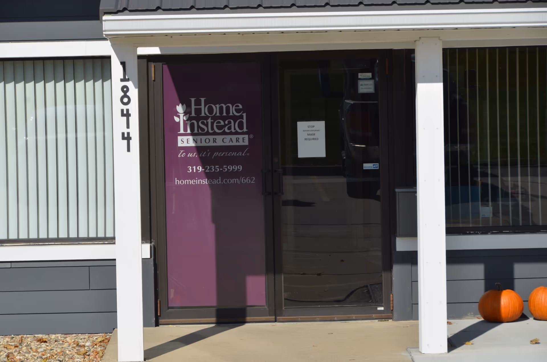 Front entrance of Home Instead Senior Care with purple door, glass, and pumpkins outside.