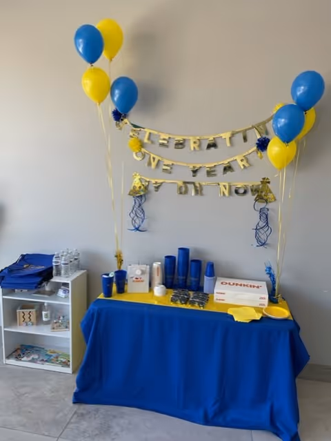 Indoor party setup with blue and yellow balloons and banner.