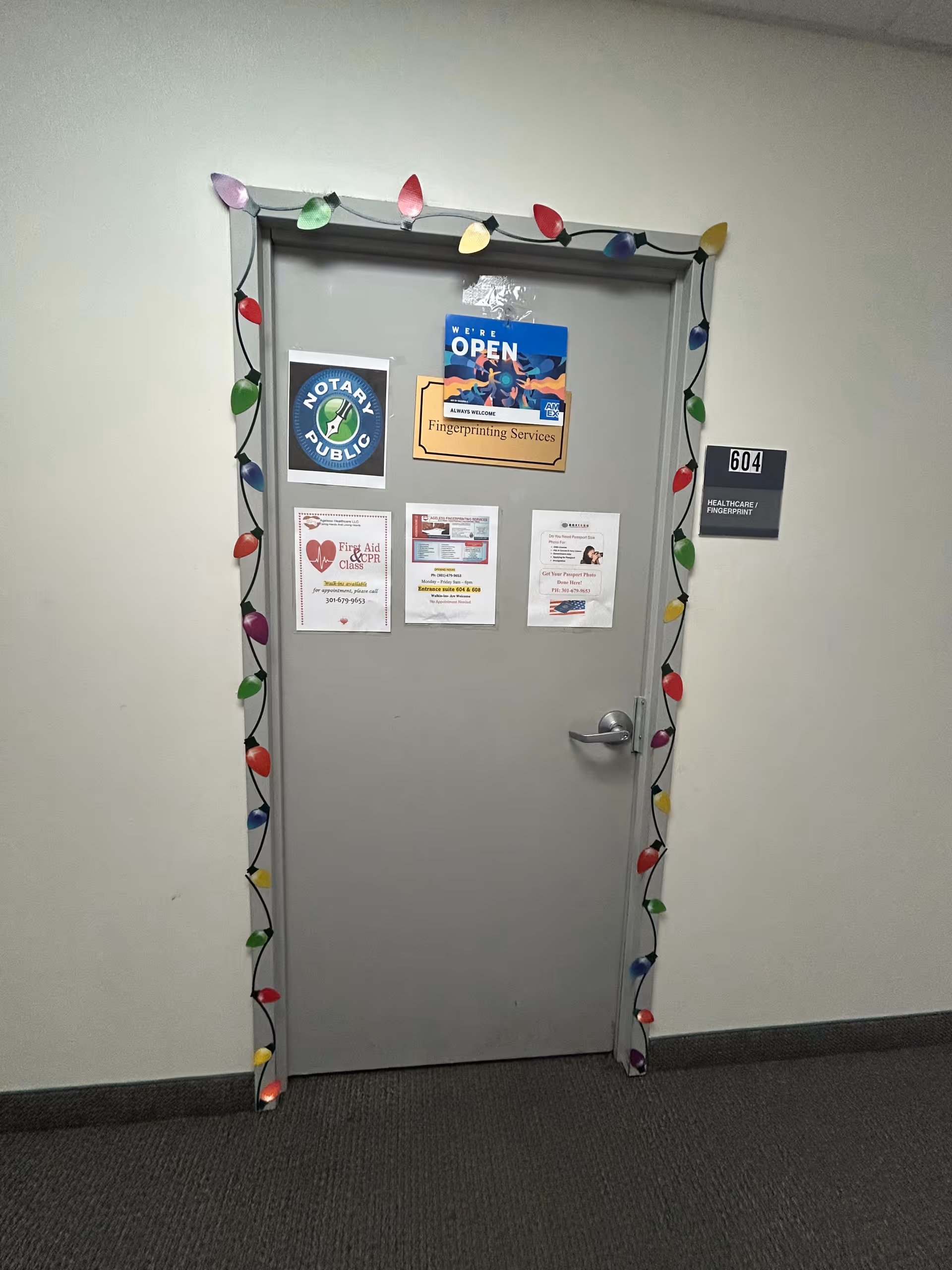 Gray interior door decorated with colorful string lights and posted notices.