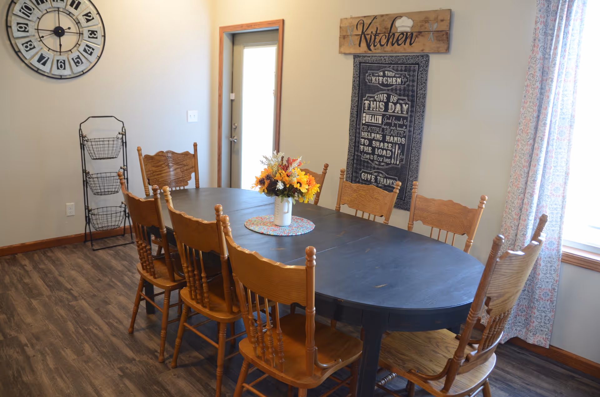 Dining room with round table, wooden chairs, and a floral centerpiece.