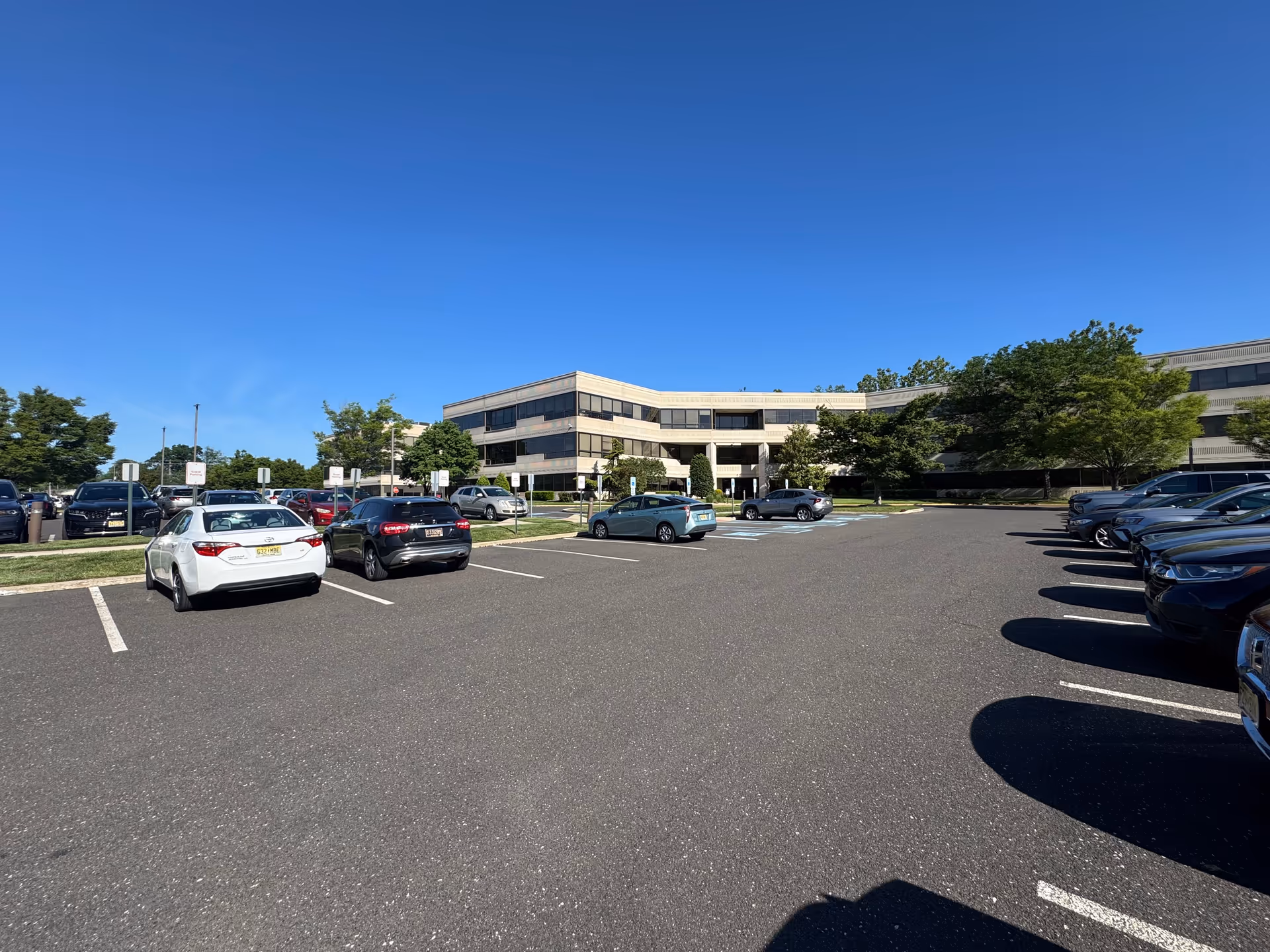 Exterior of BAYADA Global Support Center building with a spacious parking lot and blue sky.
