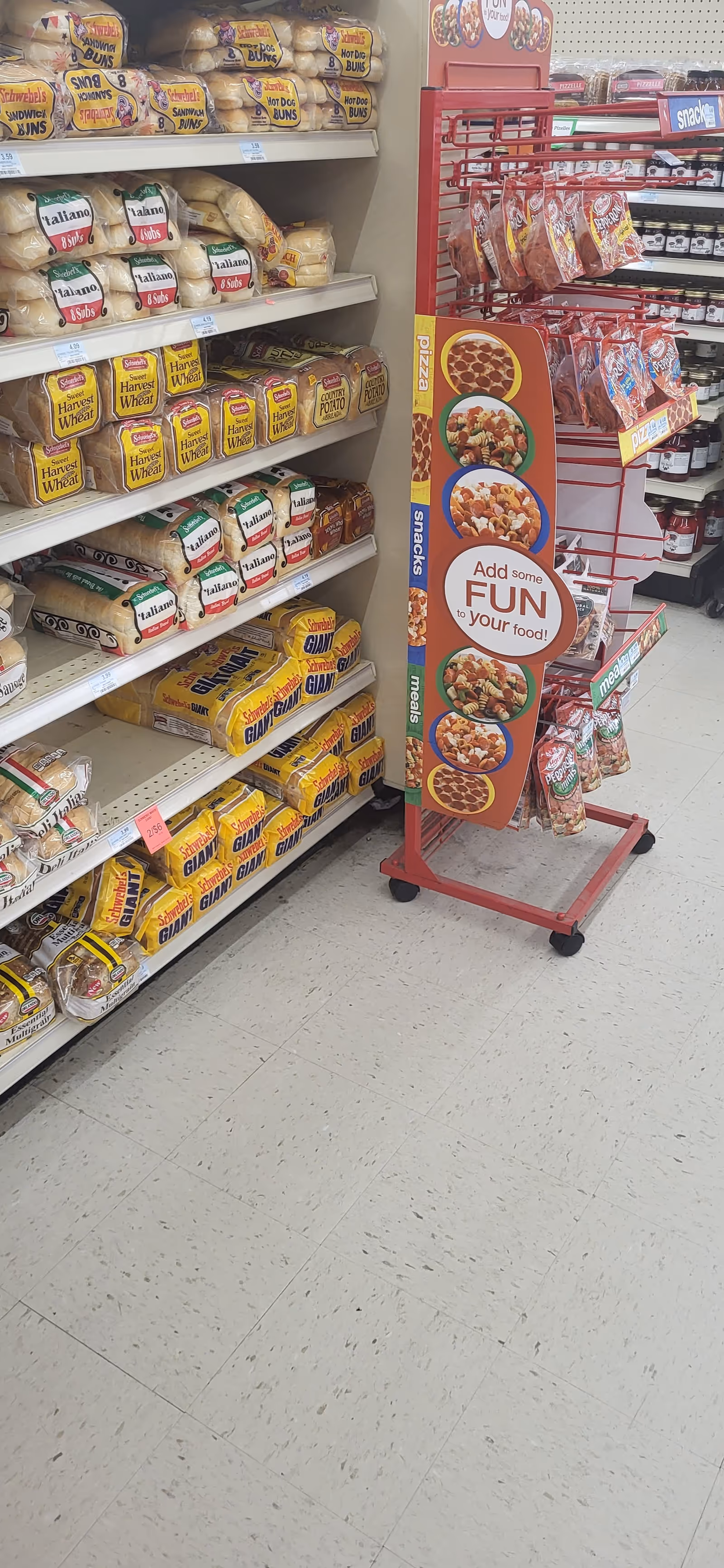 Rows of bread loaves on shelves beside a red promotional display in a grocery aisle.