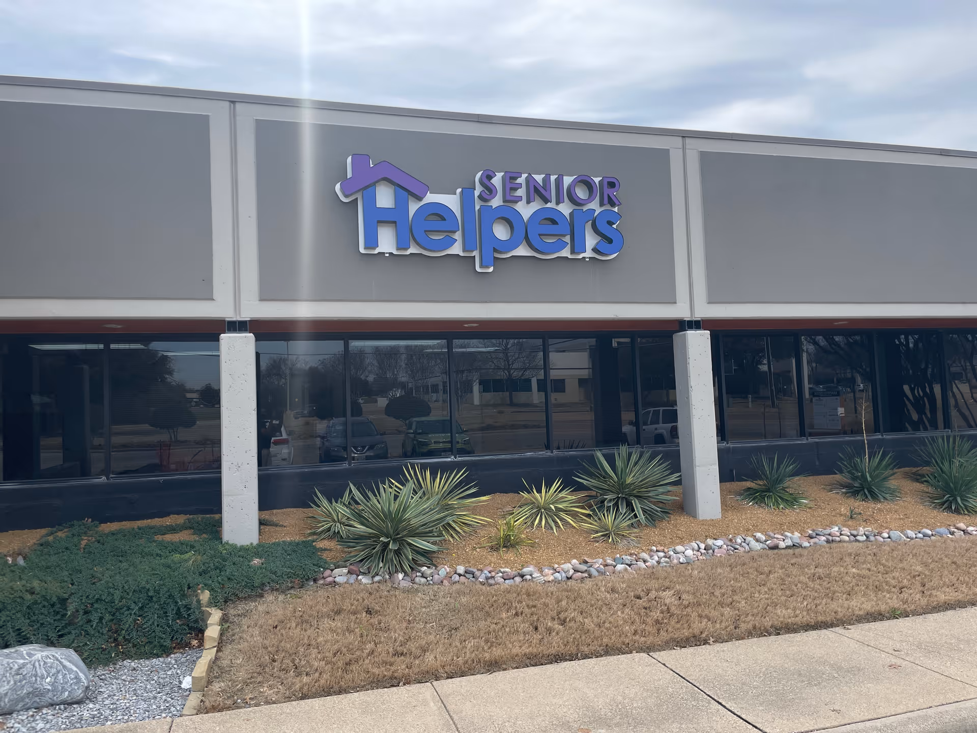 Exterior view of a Senior Helpers facility with a large front sign and landscaping.