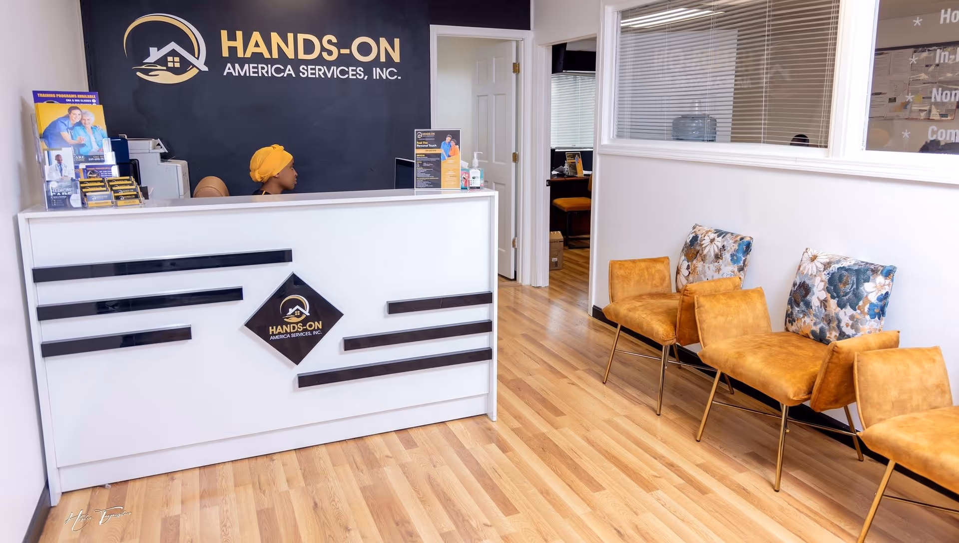 Reception area of Hands-on America Services with front desk and orange chairs