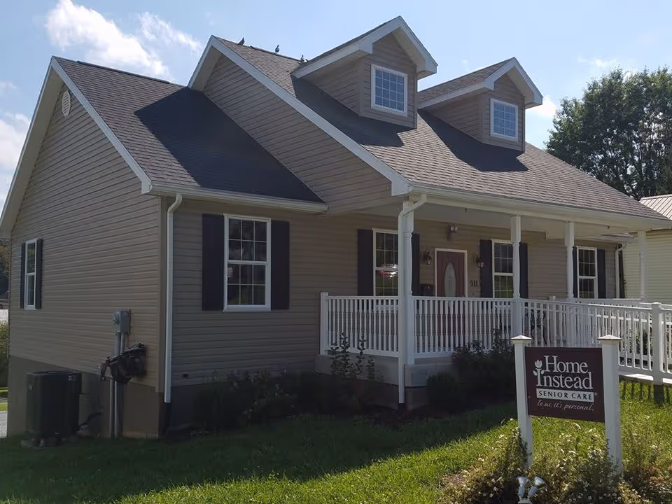 A single-story house-style senior care facility with a wraparound porch and Home Instead sign.