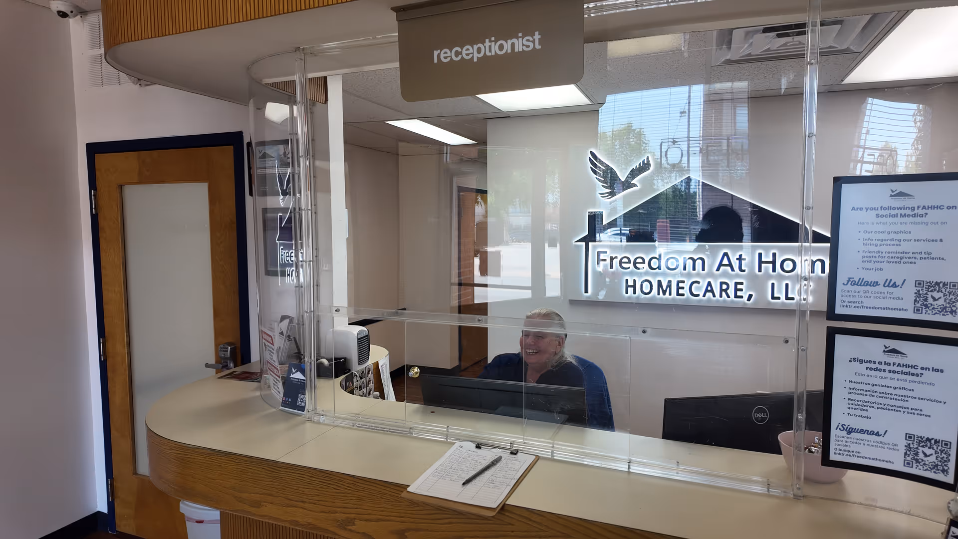 Reception area of Freedom At Home HomeCare, LLC with a receptionist behind a glass partition.