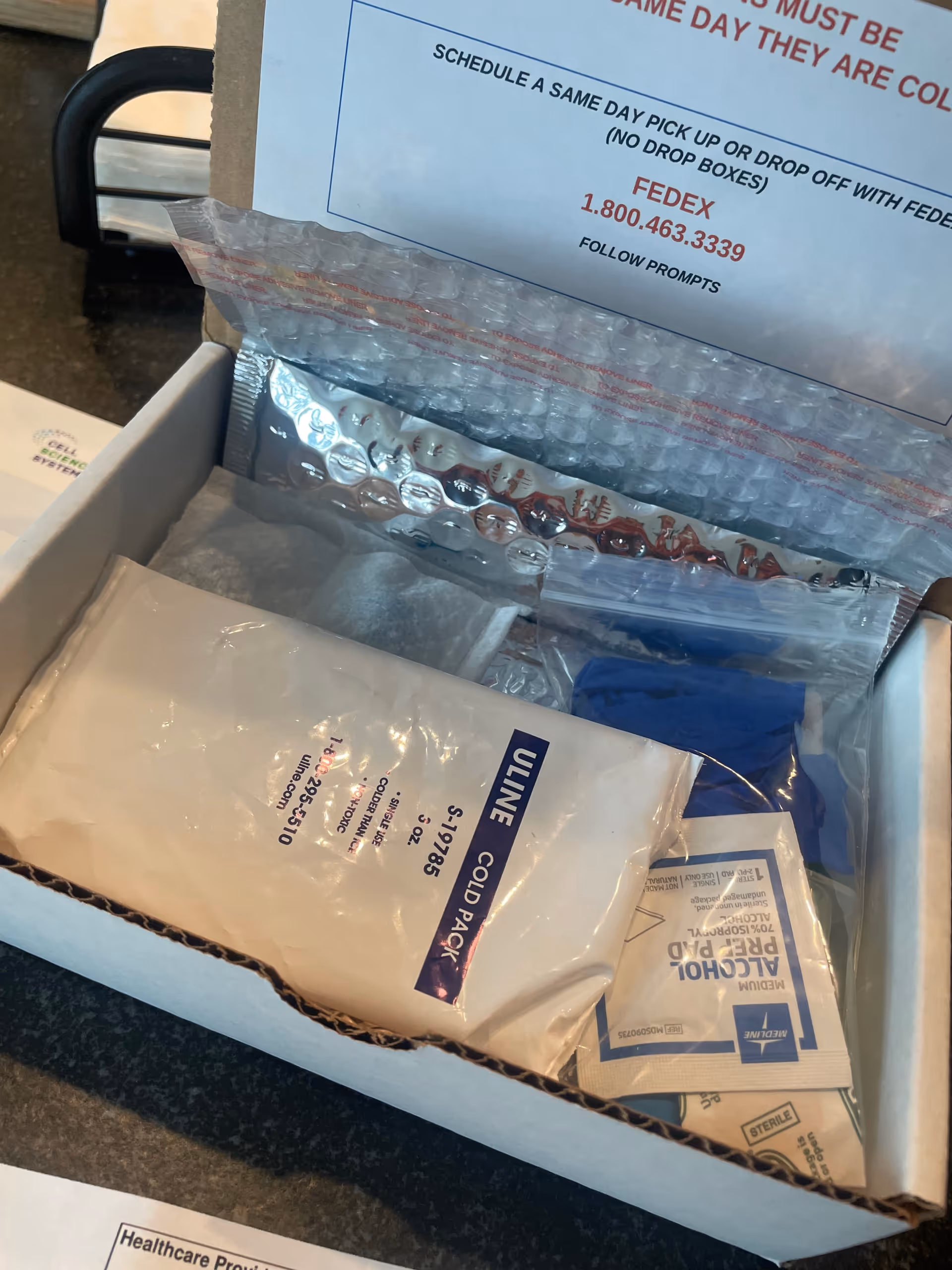 Open box of medical supplies on a dark countertop inside a facility.