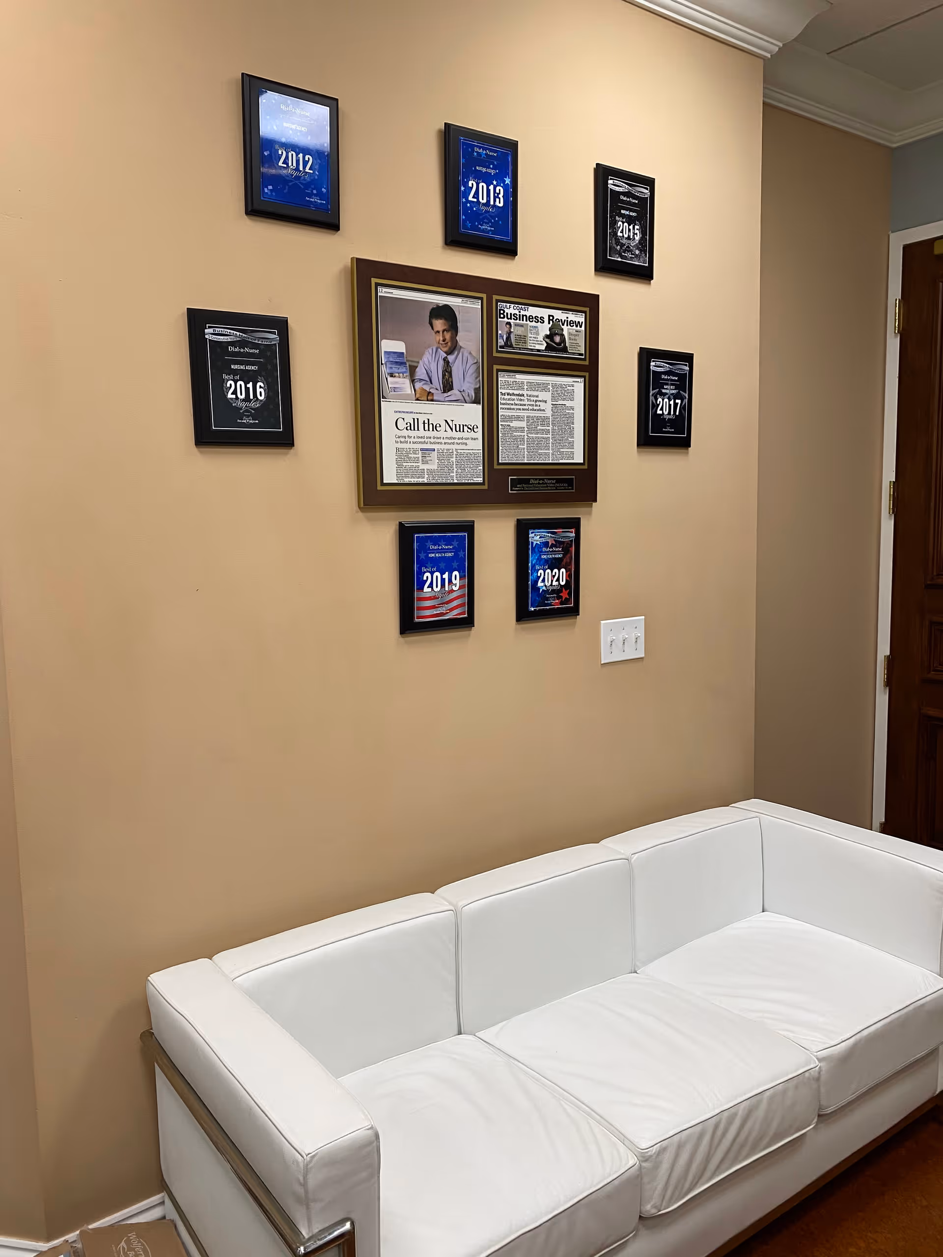 Beige interior with framed articles and a white leather couch in a waiting area.