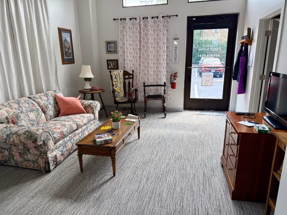 Floral sofa, coffee table, and TV visible in a cozy senior living living room.