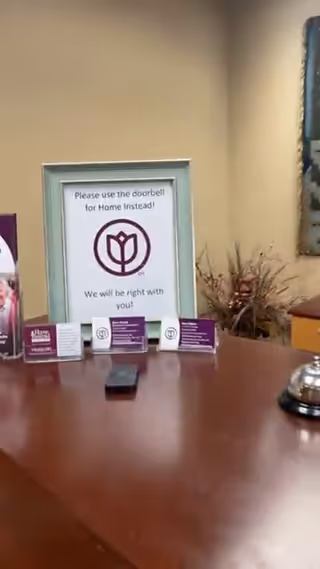 Indoor reception desk with a framed Home Instead sign and business cards.