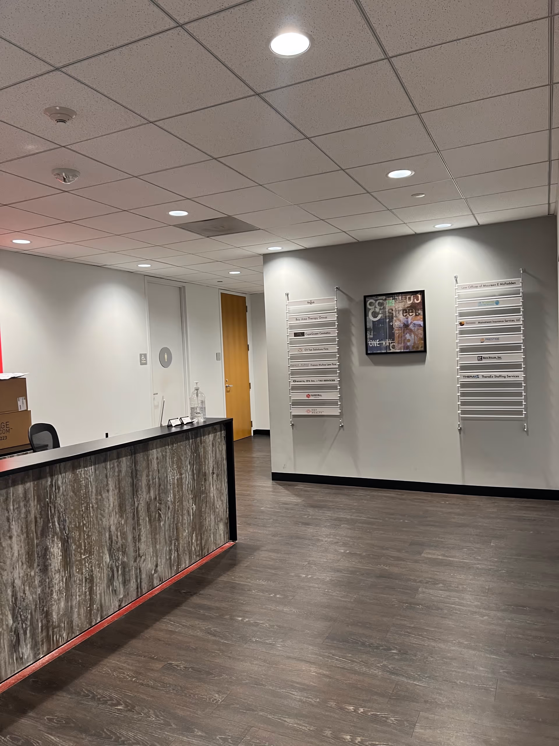 Reception desk with wood panels, hallway, and wall signage in a senior facility lobby.