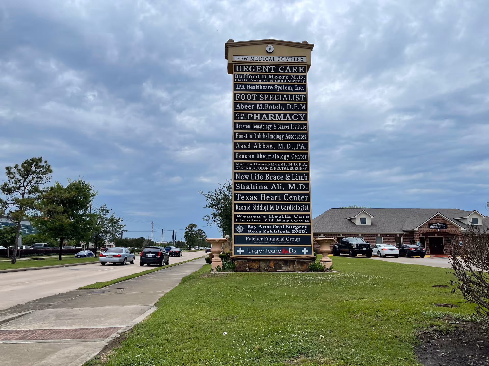 Tall IPR Healthcare System sign outdoors with parked cars and a building in background.