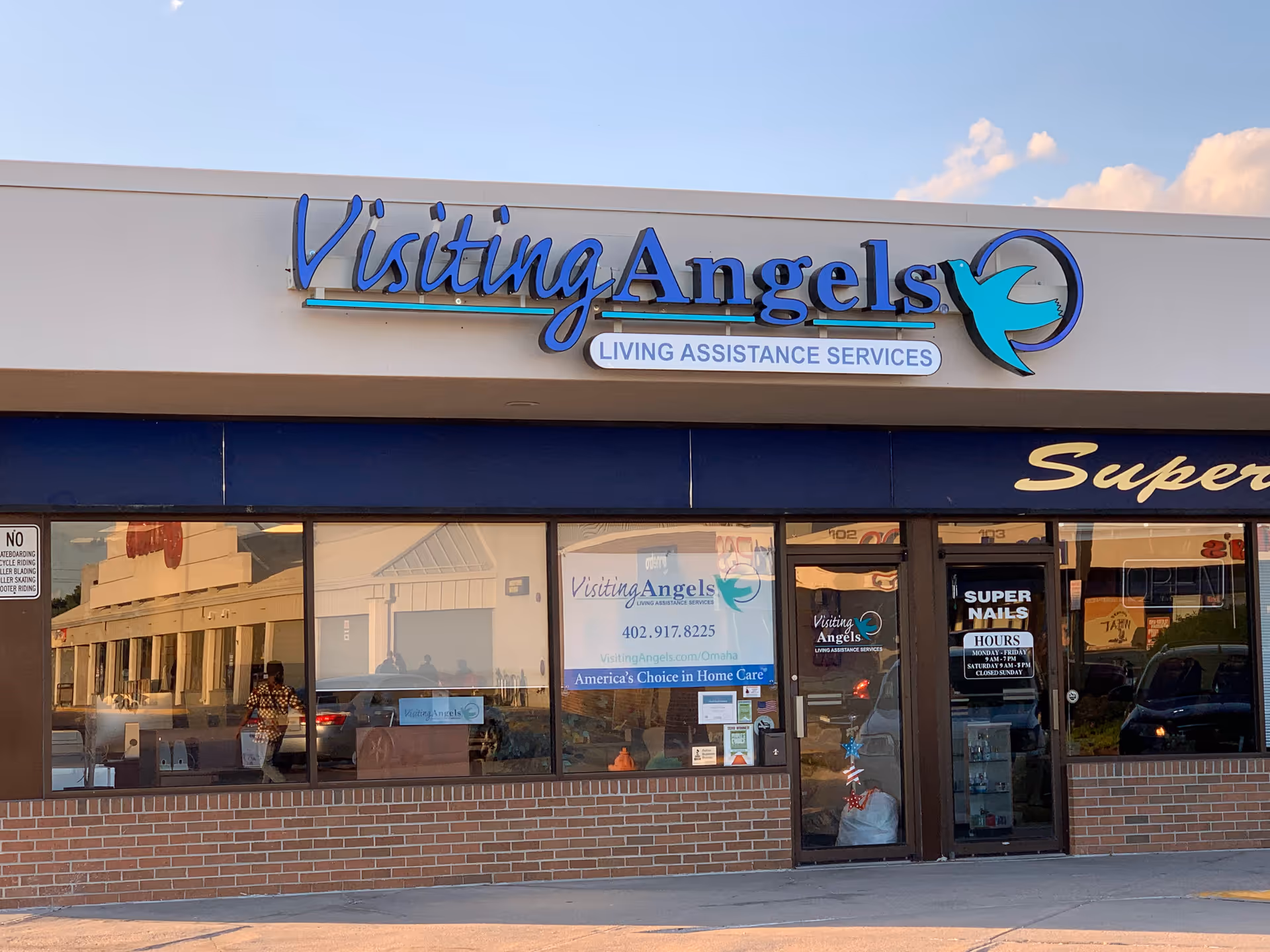 The storefront of Visiting Angels Senior Home Care features a blue sign and glass windows.