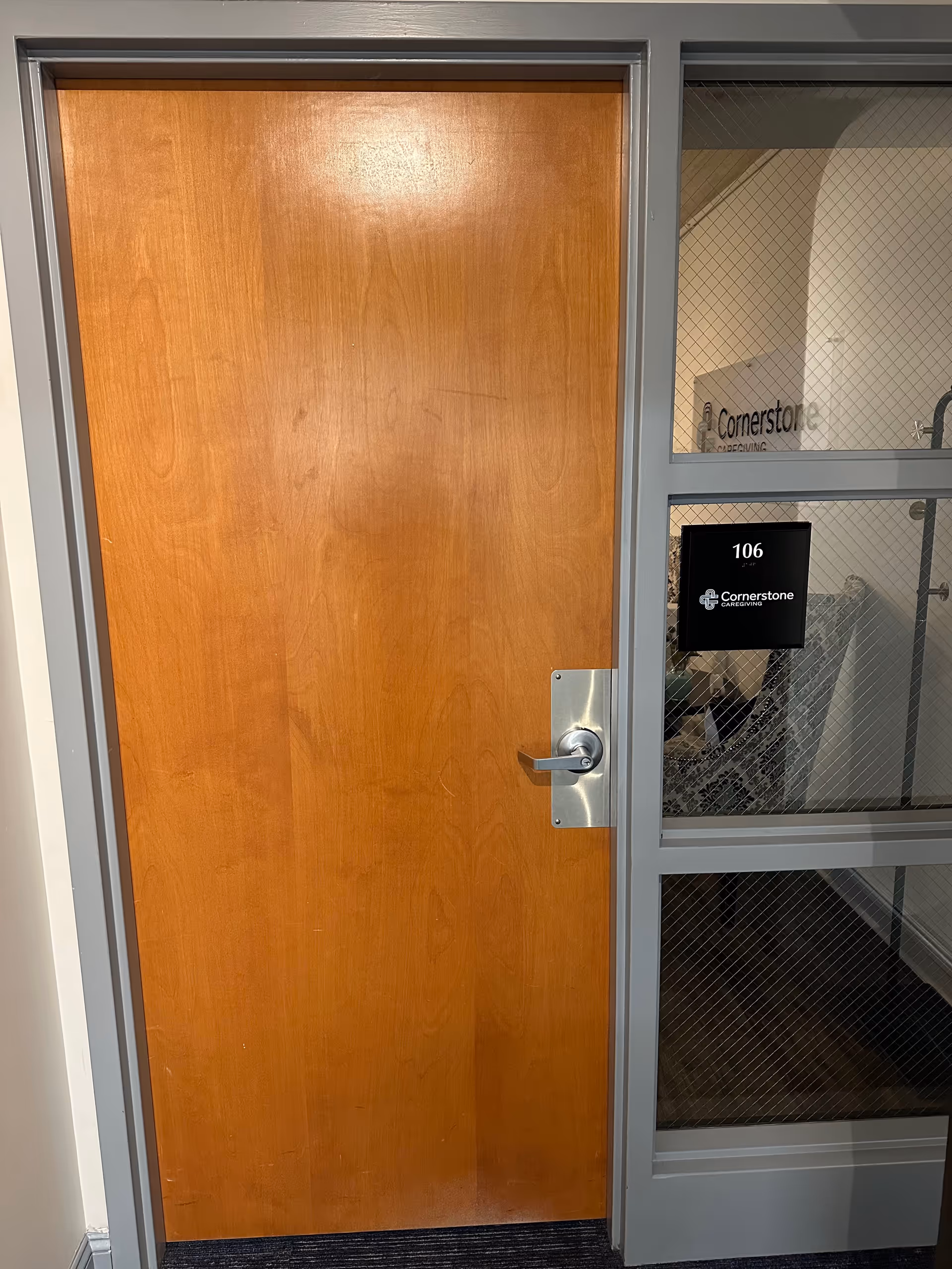 A wooden interior door next to a glass panel with a room number plaque 106.