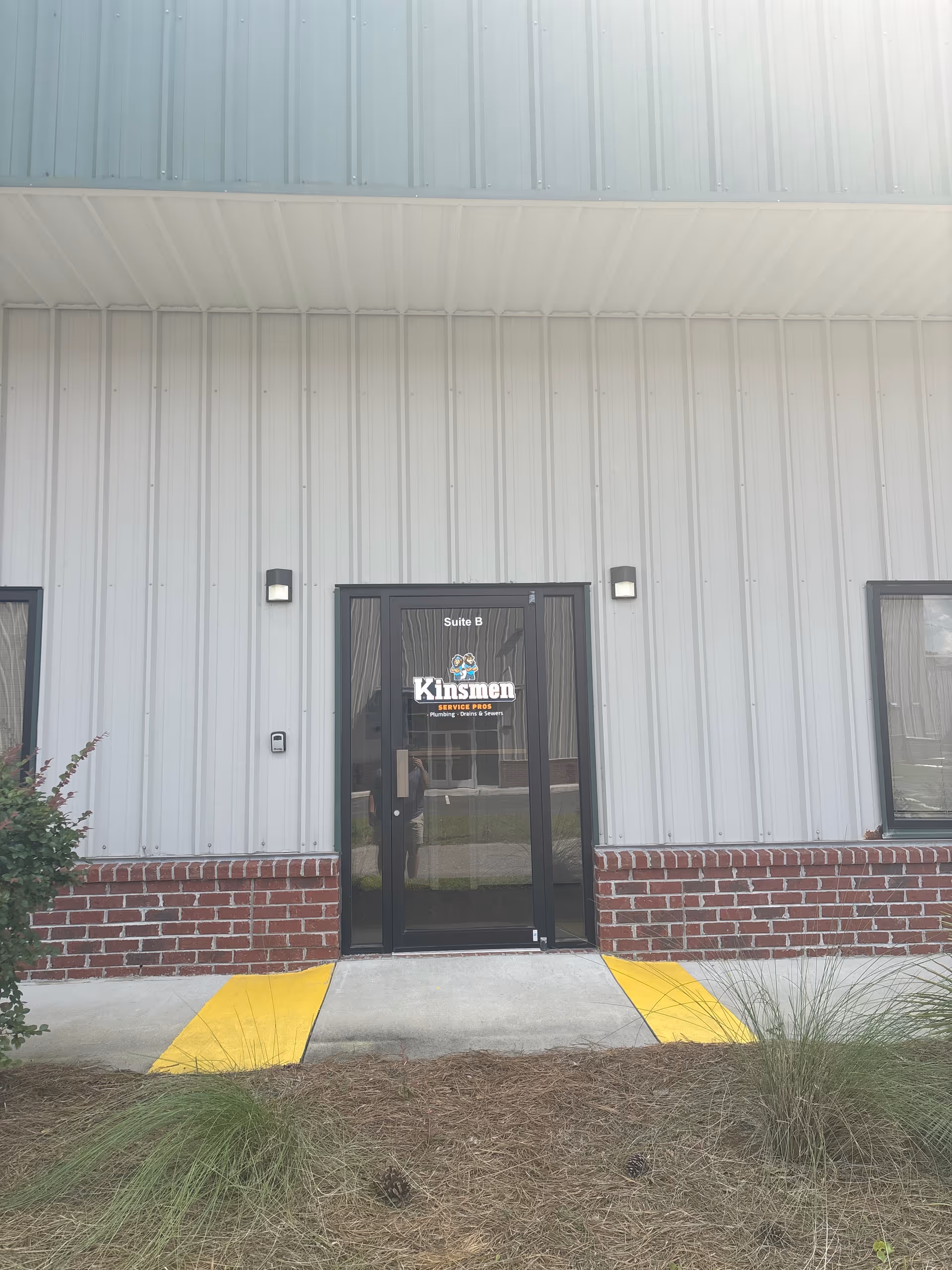 Exterior view of a facility entrance with glass door and yellow ramp.