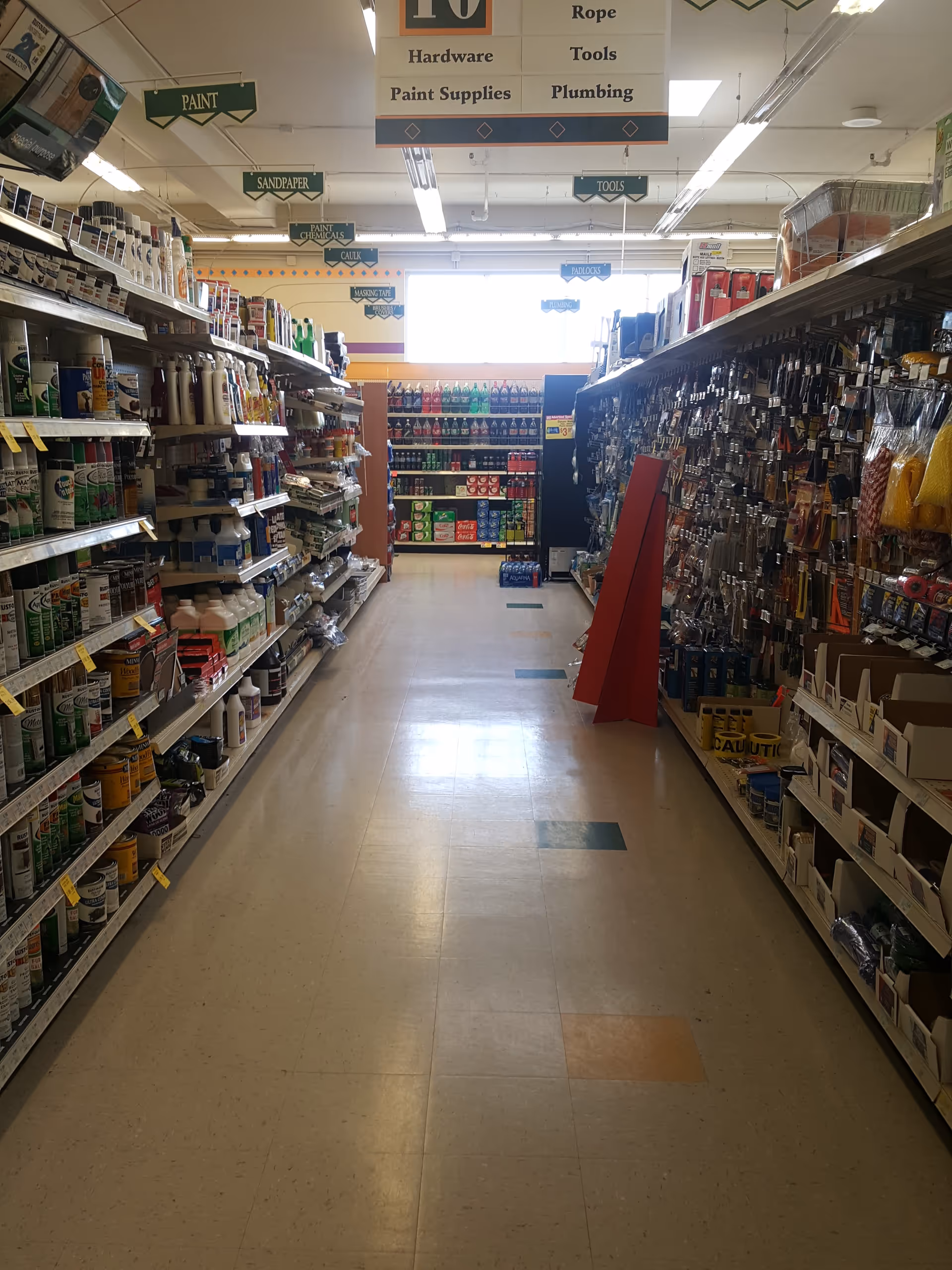 Interior store aisle with shelves stocked with cleaning and hardware supplies.