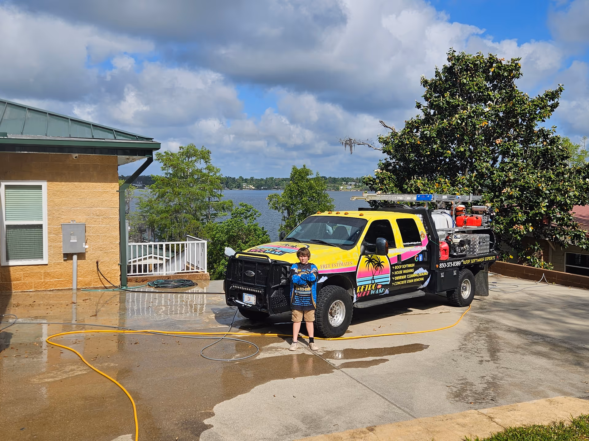 Bright yellow service truck with logos parked outside a building under a cloudy sky.