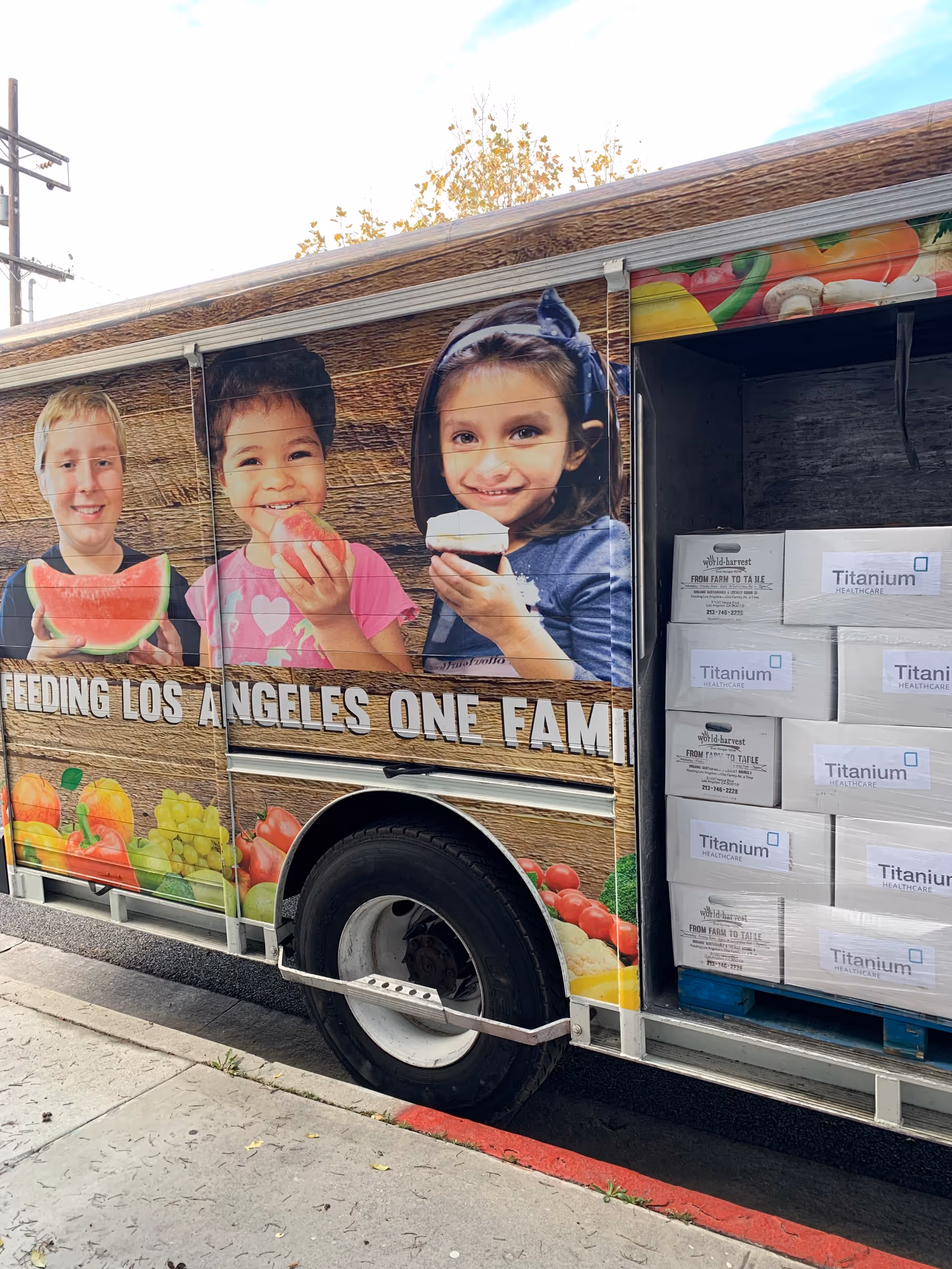 Exterior side of a colorful delivery truck showing children eating fruit and Titanium boxes.