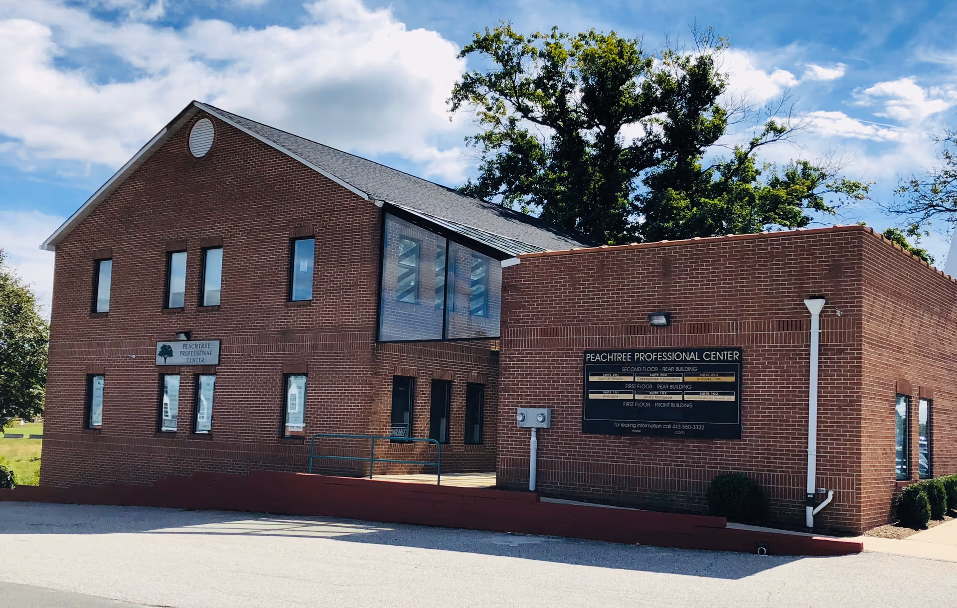 Red brick building exterior with front entrance and signage under a blue sky.