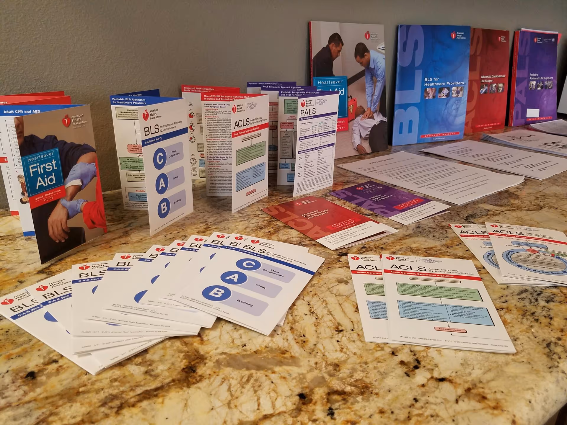Table covered with CPR training brochures and pamphlets on a granite counter.