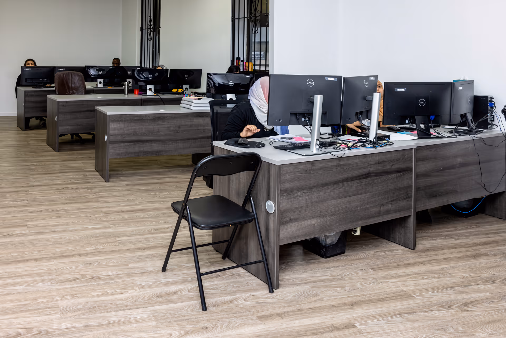 There are rows of desks with computer stations and staff inside a senior care facility.