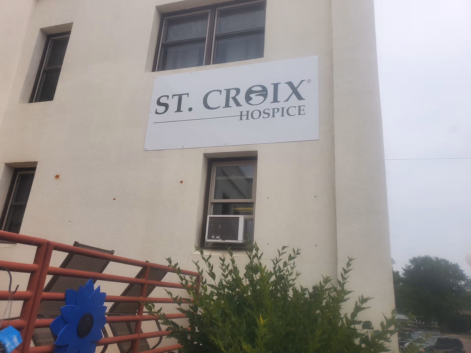 Exterior view of a beige building with a St. Croix Hospice sign and railing.