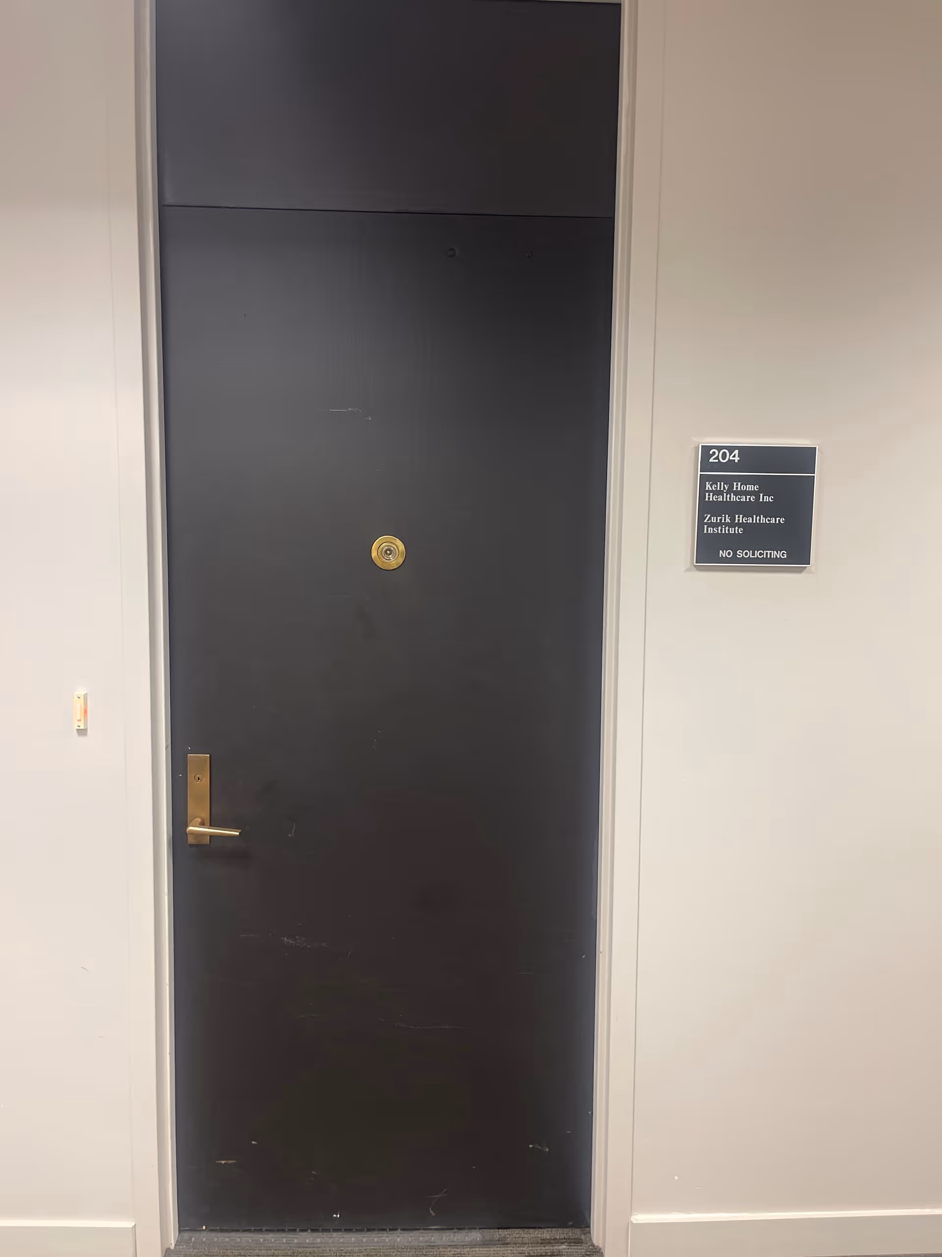 Tall dark metal door in a hallway, with plaque on the side.