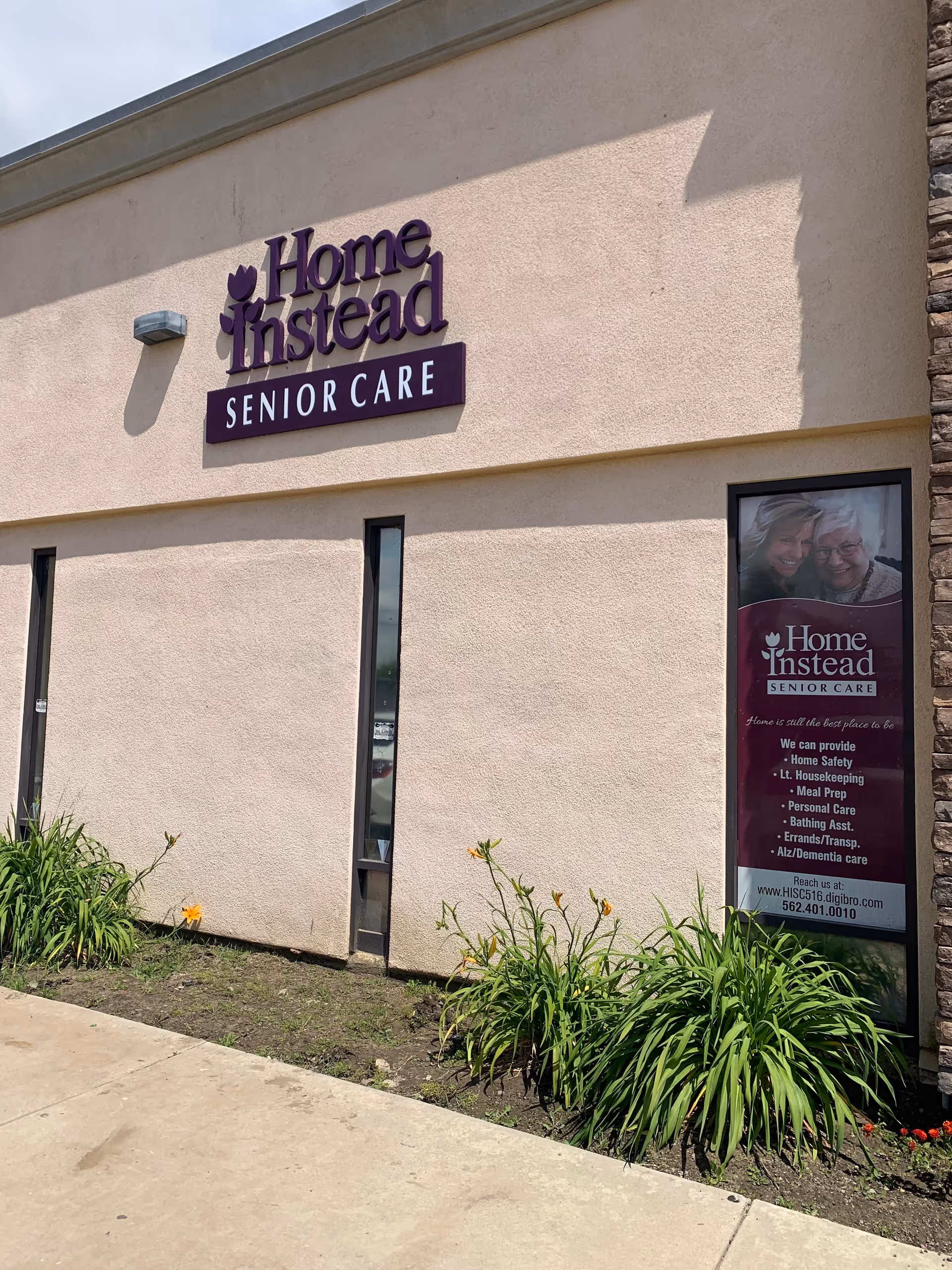 Exterior view of a Home Instead Senior Care building with sign and plants