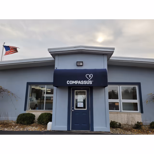 Blue Compassus building entrance with awning and American flag.