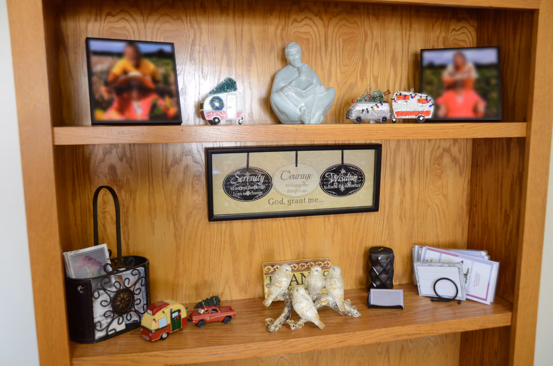 Wooden built-in shelf displaying framed photos, statues, and decorative trinkets.