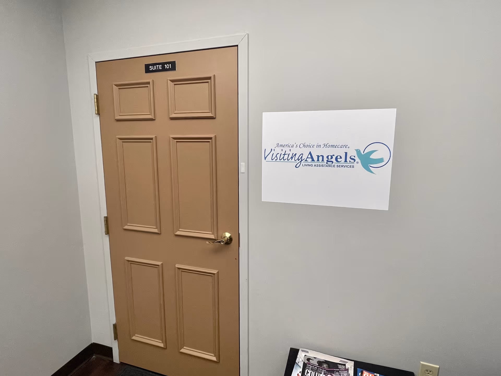 Beige suite door labeled Suite 101 in a hallway with a Visiting Angels sign