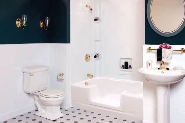 Bright white bathroom with a toilet, walk-in tub, and pedestal sink.