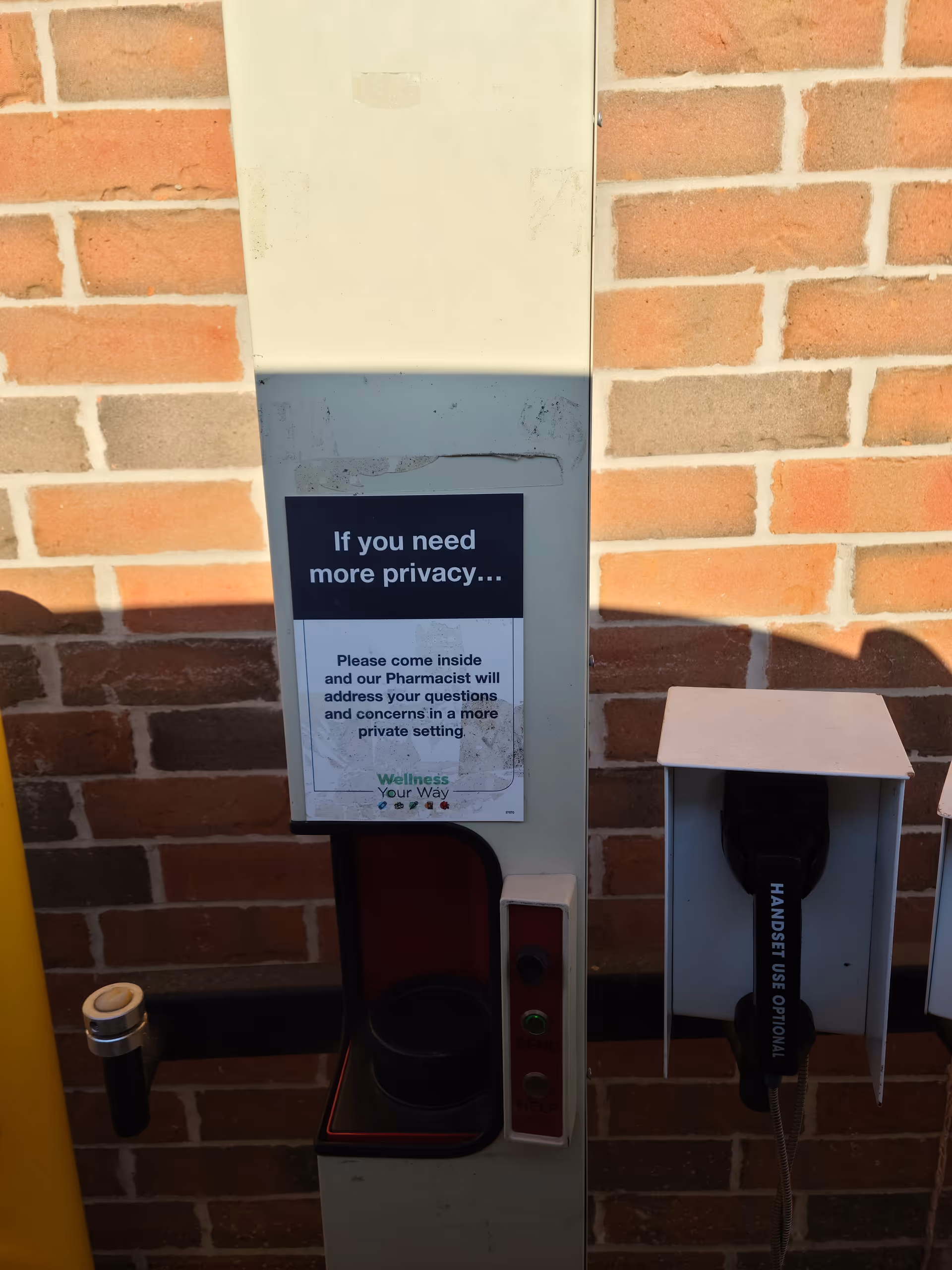 A privacy sign on a tall white kiosk beside a wall-mounted handset.
