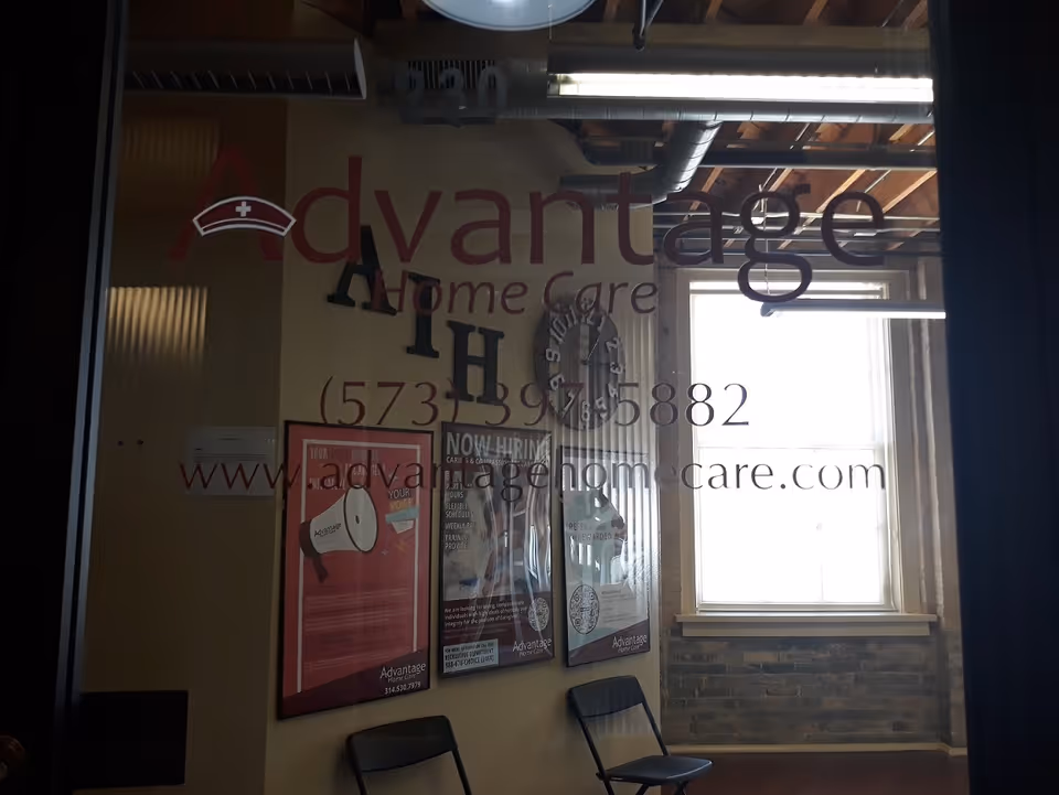 Interior lobby area with Advantage Home Care signage, posters, window, and chairs.