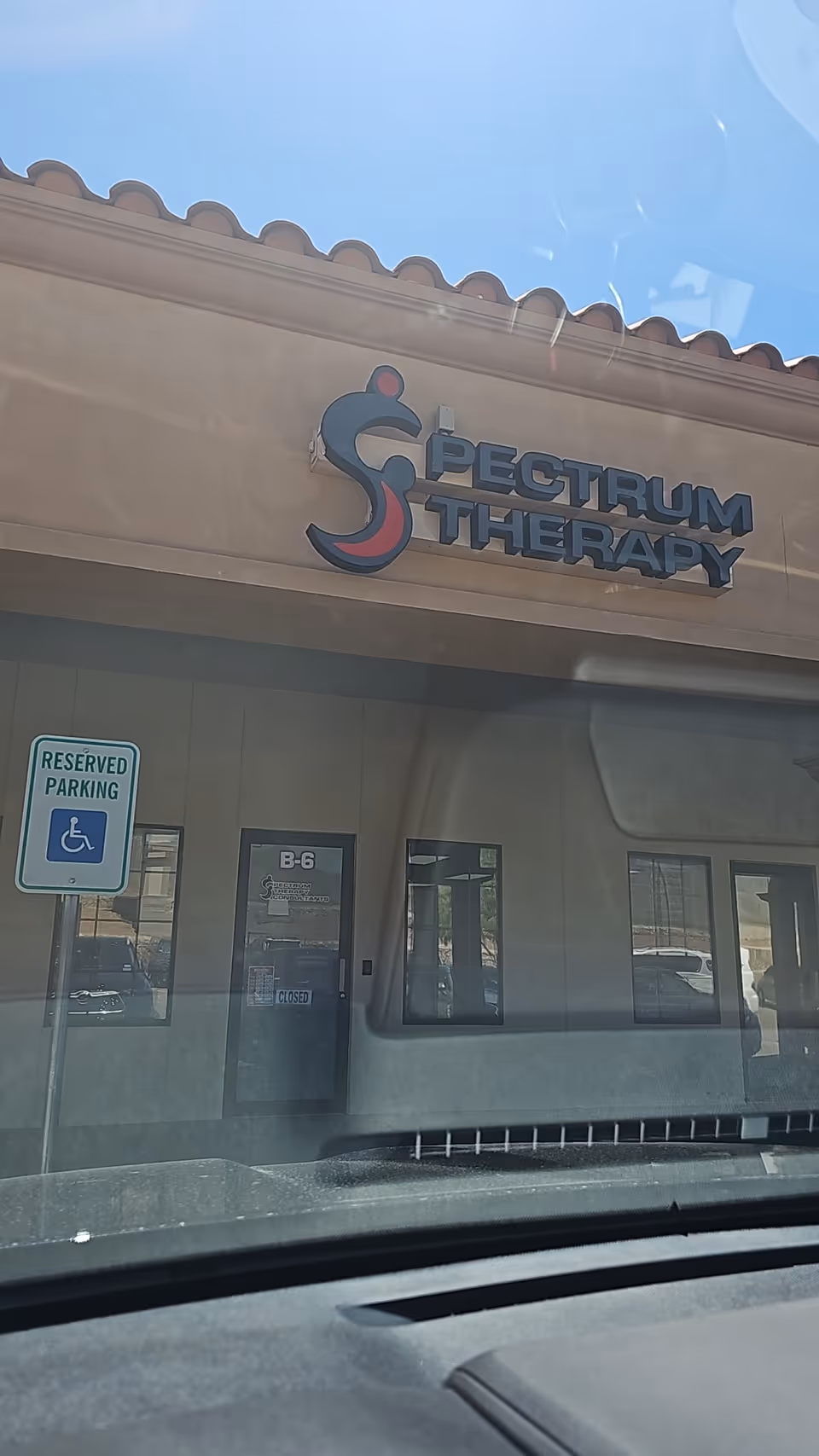 Front view of Spectrum Therapy building with logo and a reserved parking sign.
