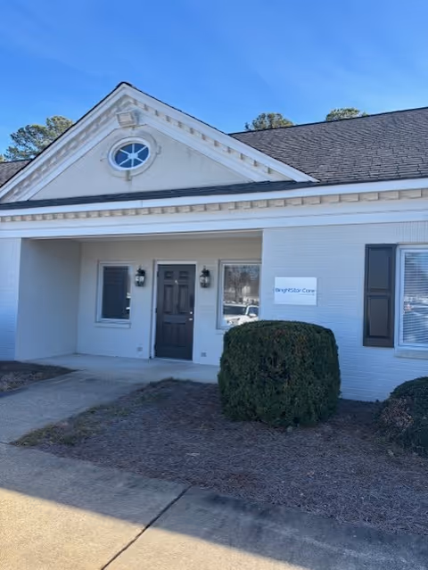 White brick BrightStar Care facility exterior with entrance and shrubs