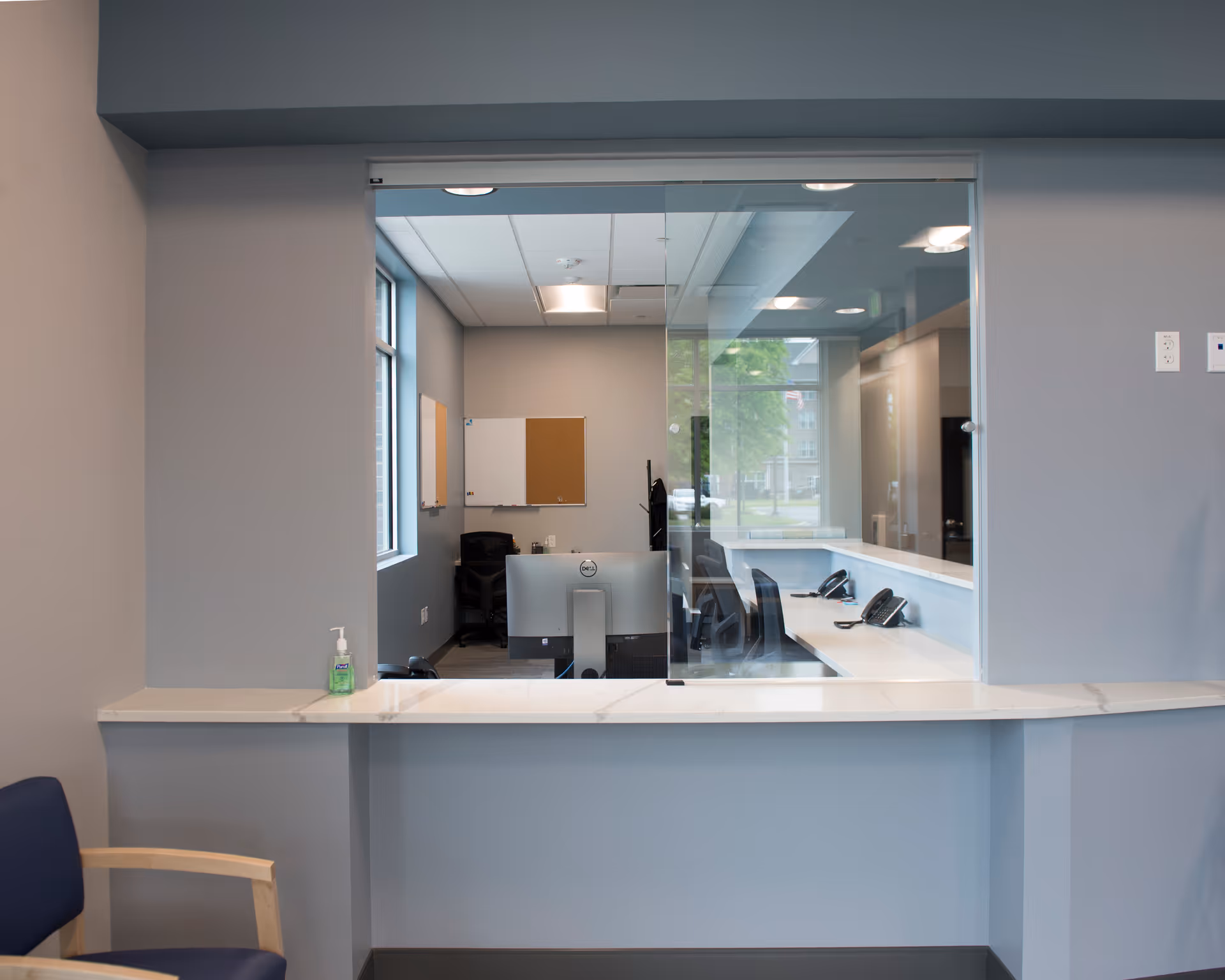 Interior reception area with a glass window, desk, and seating.