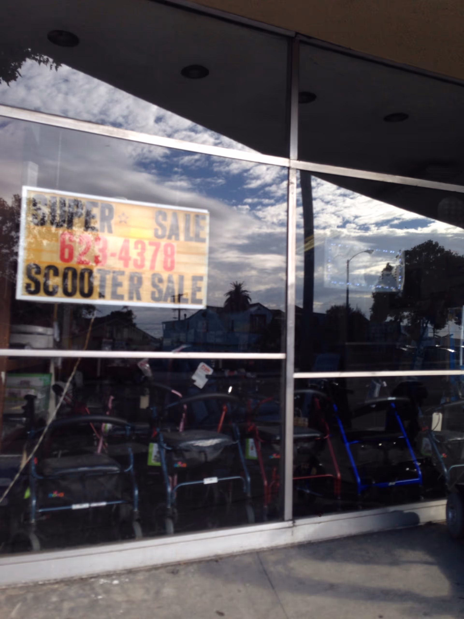 Shopfront windows display mobility scooters for sale, with a large 'SCOOTER SALE' sign.