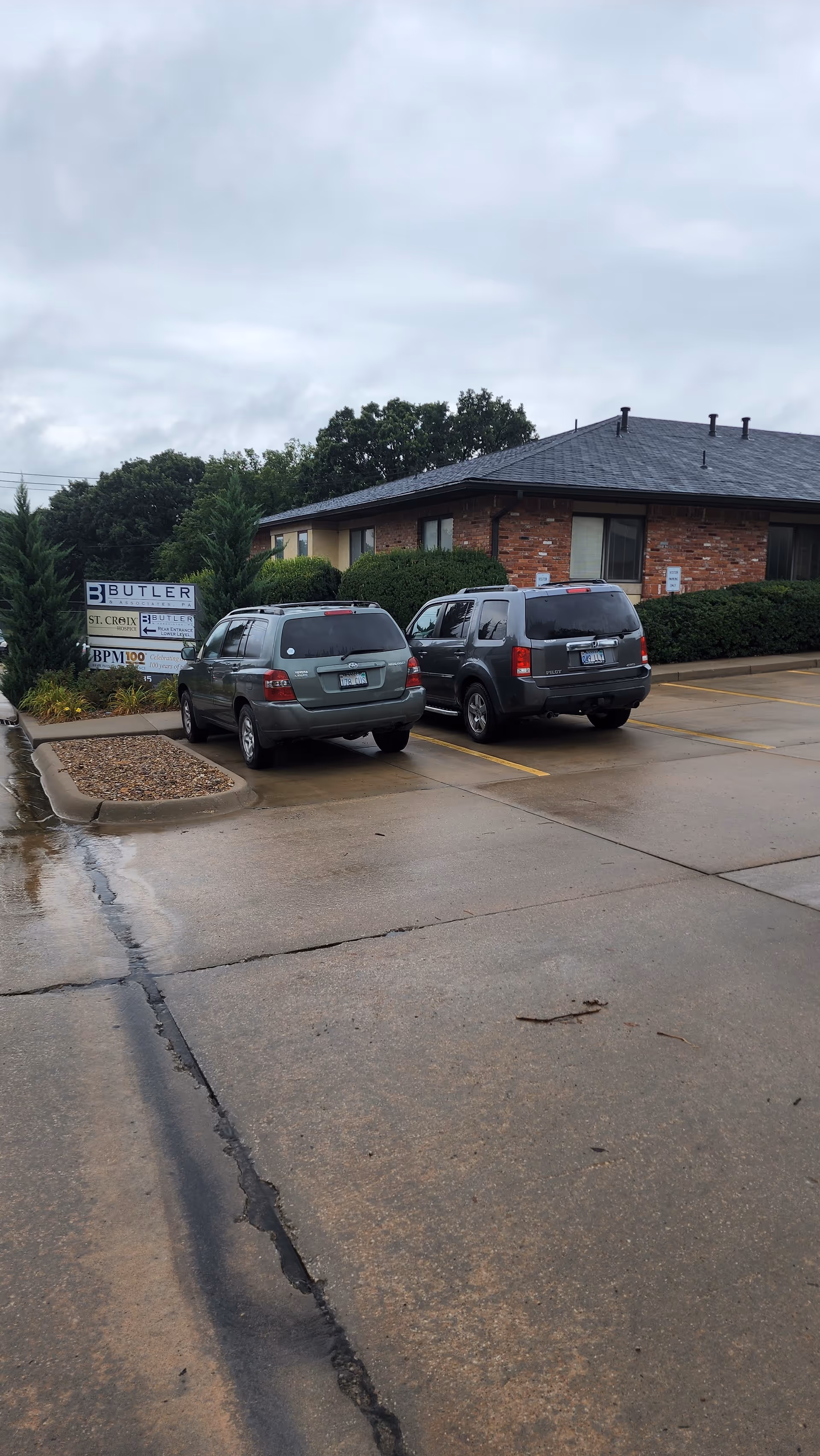 Parking lot in front of St. Croix Hospice brick building under cloudy sky.