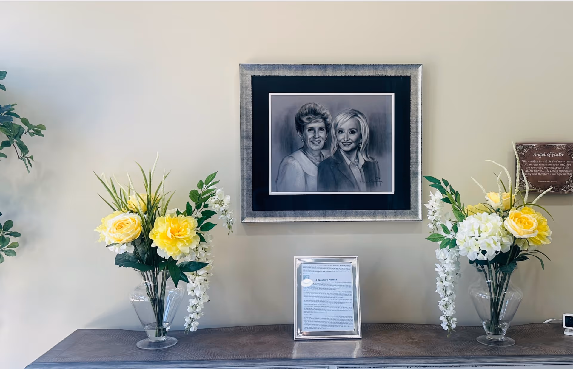 Interior display on a console with a large framed portrait and yellow flowers.