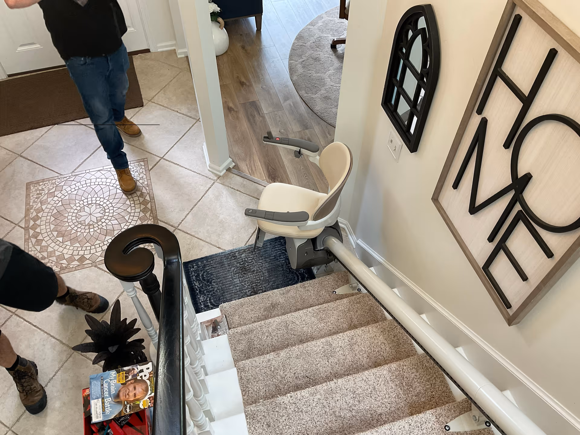 Stairlift chair attached to a carpeted staircase in a residential hallway.
