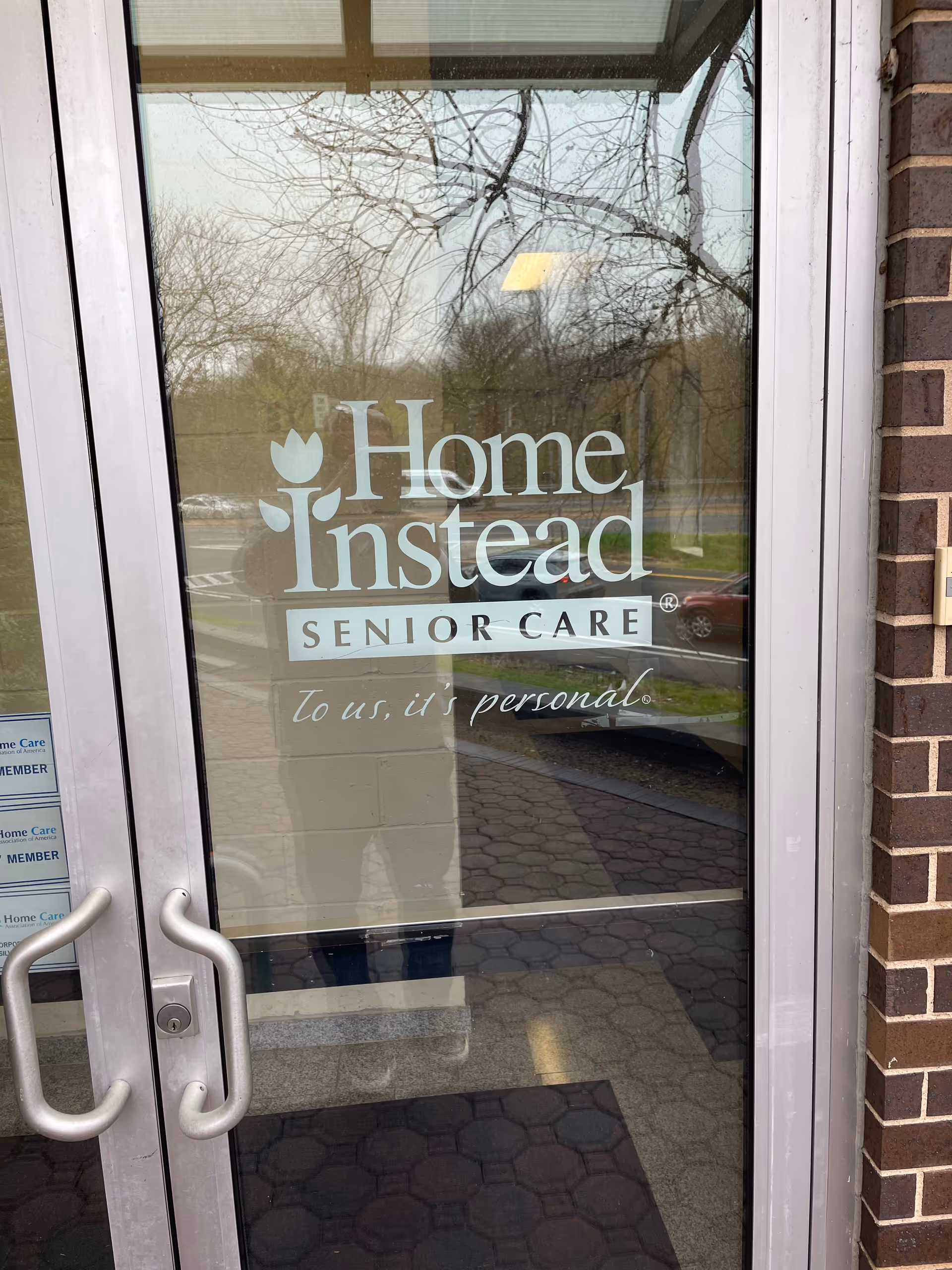 Glass entrance door with Home Instead Senior Care logo and brick exterior.