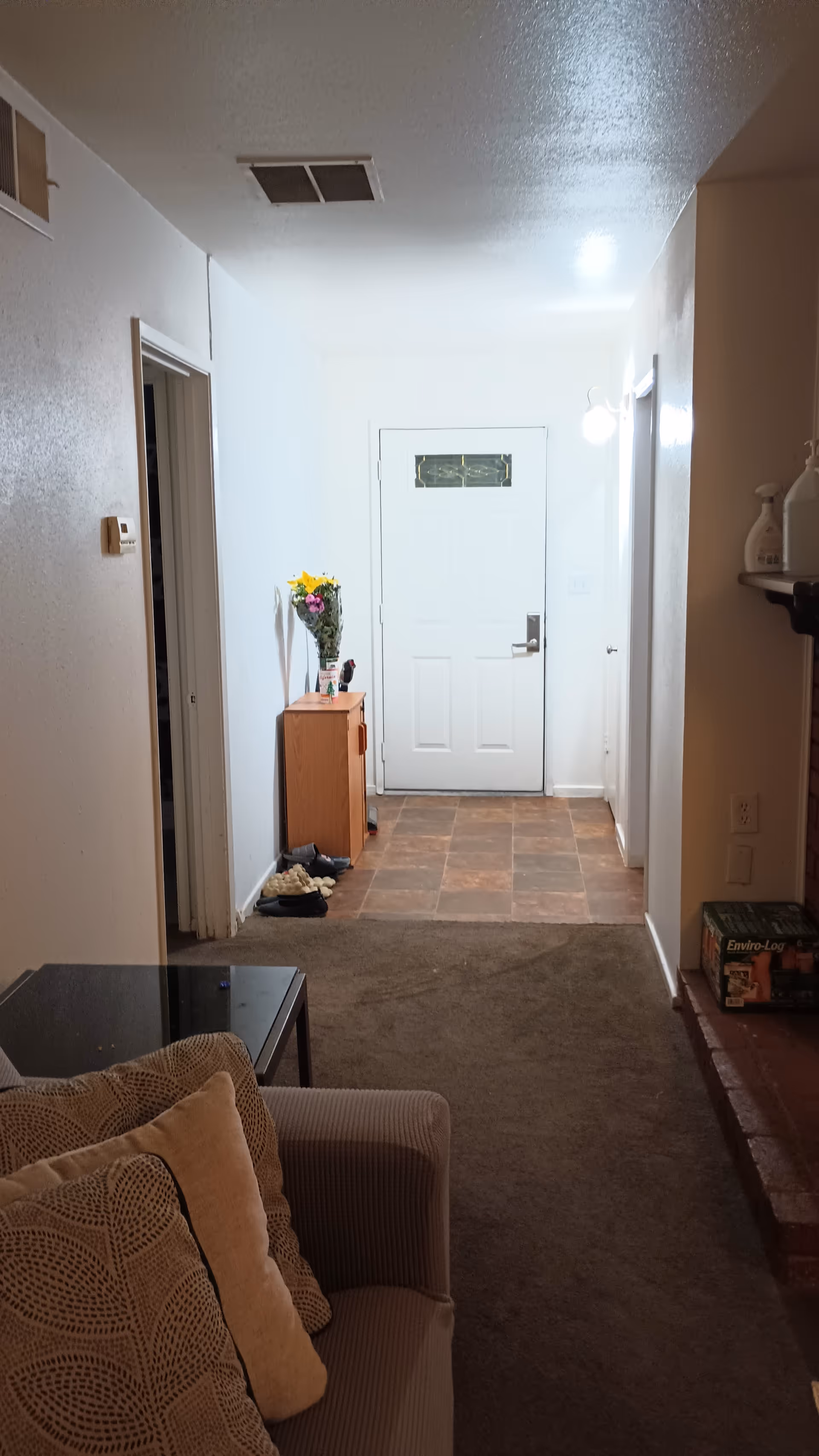 Interior hallway of a senior facility with a sofa, vase of flowers, and front door.