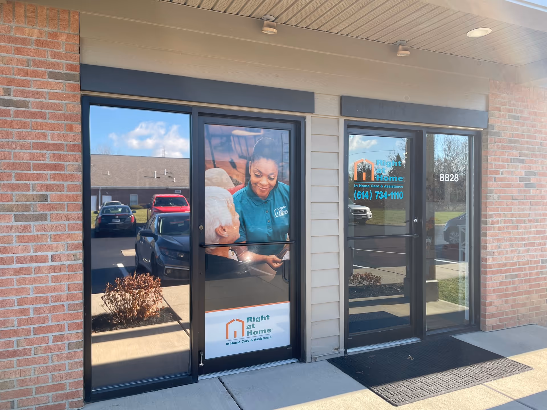 Brick exterior with glass entrance doors showing a staff image and Right at Home signage.