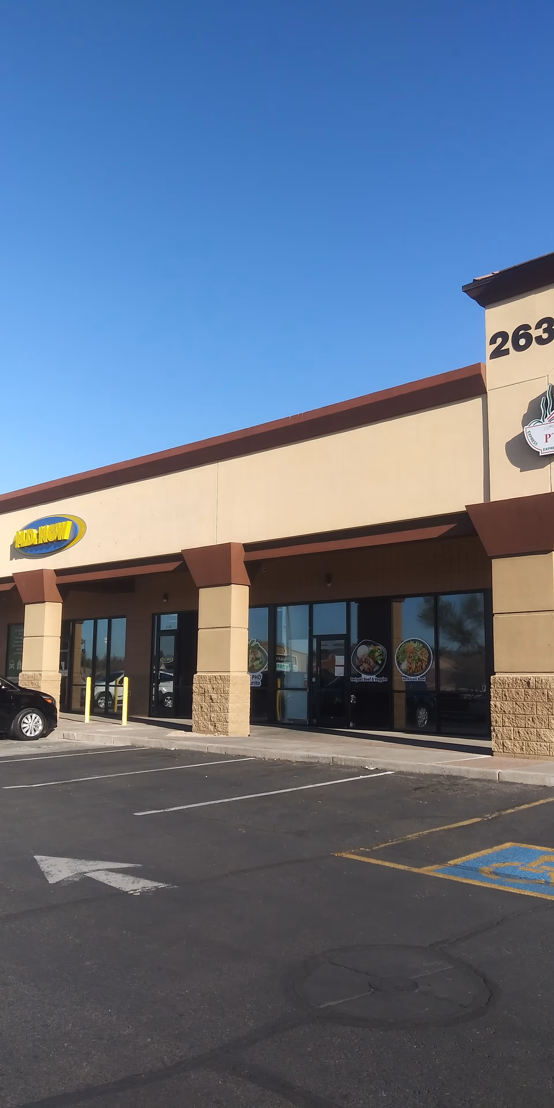 Exterior view of a beige storefront building with MY DR NOW sign and parking lot.