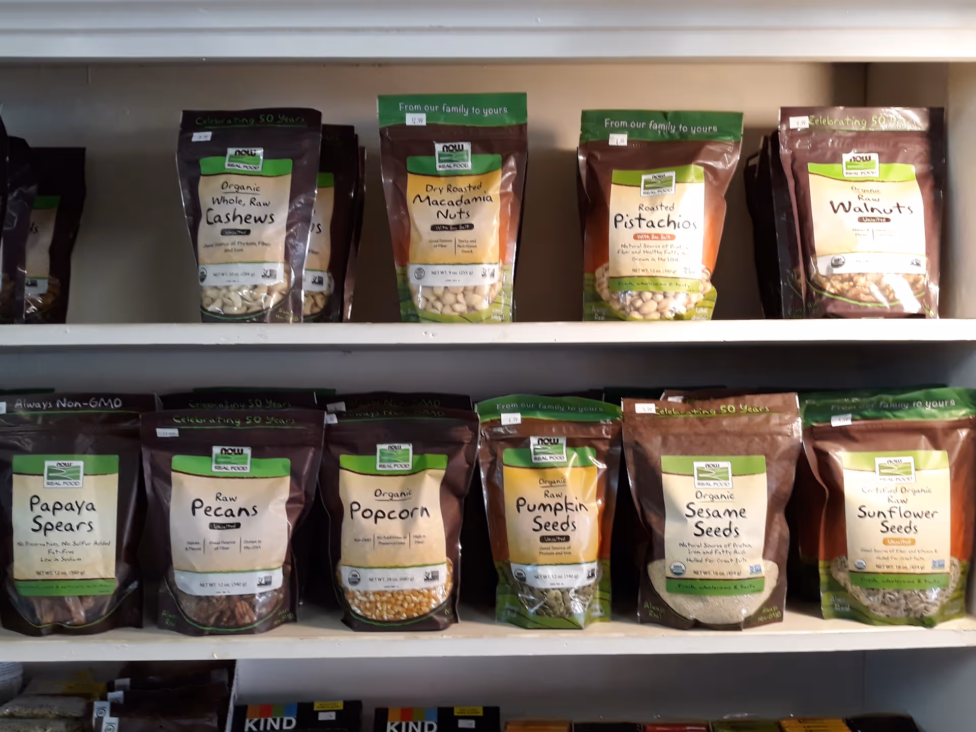 Shelf displays assorted snack bags of nuts and seeds arranged in rows.