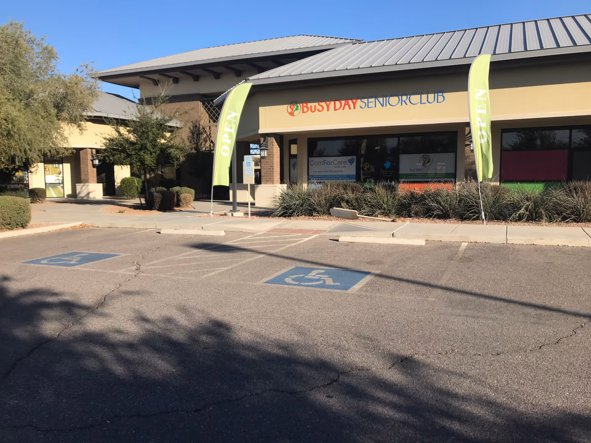 Front of a single-story building with Busy Day Senior Club and ComForCare signage and handicap parking.
