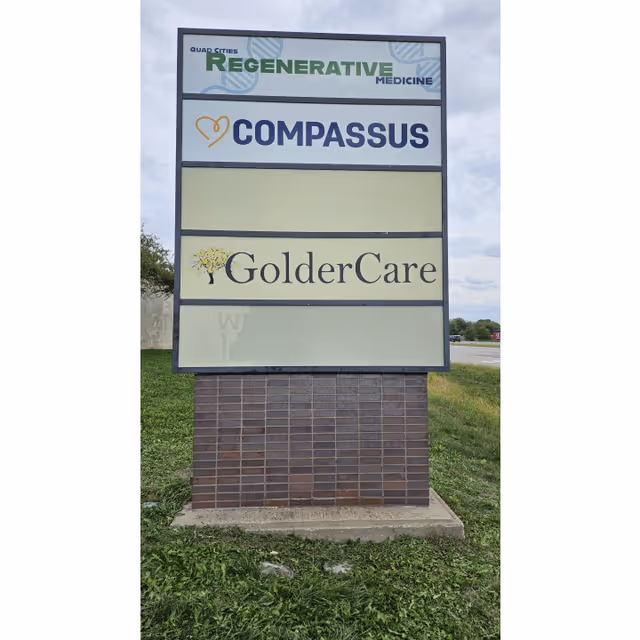 Outdoor signboard displaying Compassus and GolderCare names on a brick pedestal
