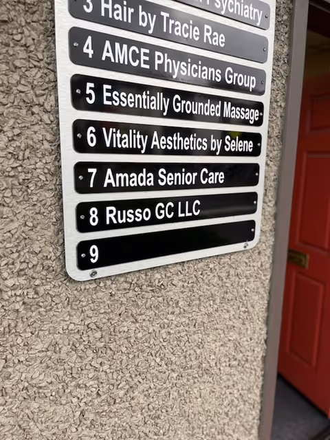 Exterior wall with tenant signs and a red door, featuring Amada Senior Care among others.