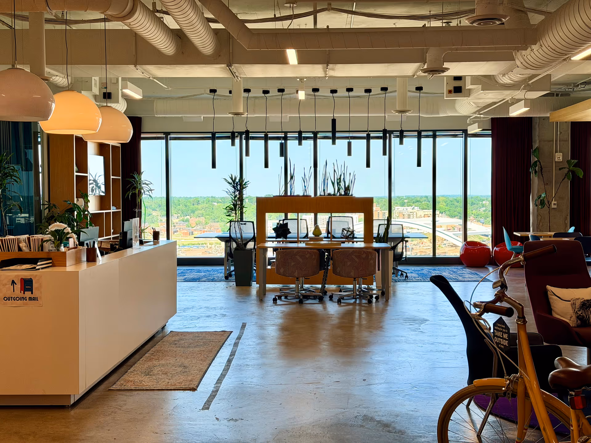 Bright, modern reception and lounge area with long desk, seating, and expansive windows.
